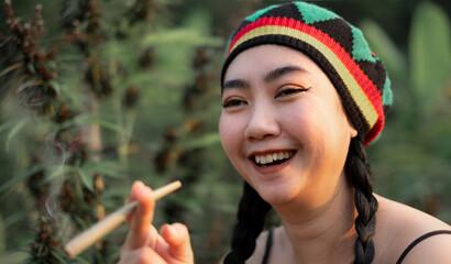 Yong Asia woman smoking marijuana at cannabis tree plant background