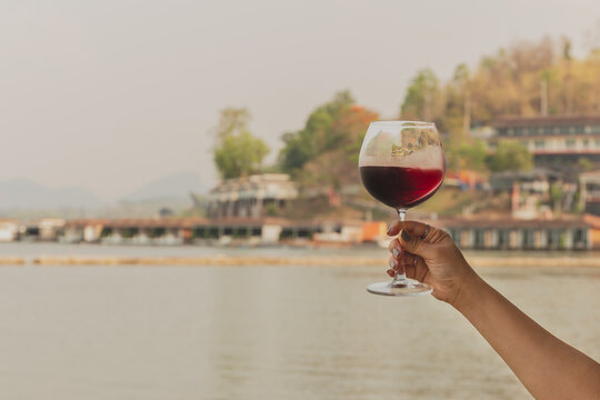 Feman hand holding glass of red wine.
