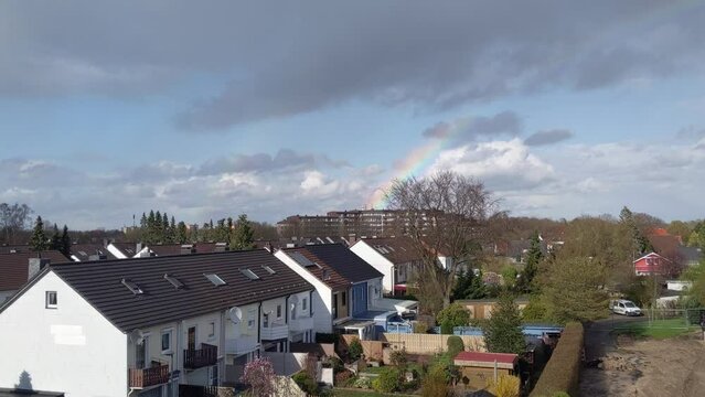 Double rainbow disappearing above the houses in residential neighborhood