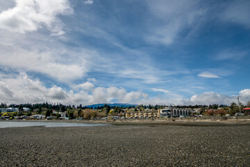 Bare rocks are exposed on Departure Bay Beach at low tide on a sunny day in early springtime. View of the residences along Departure Bay Road, Nanaimo, BC, Canada.