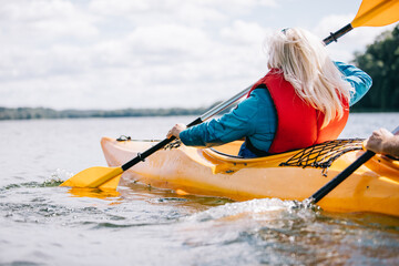 Happy senior active couple kayaking on lake