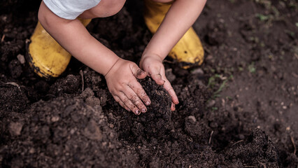 Earth day activities for kids, small kid playing with soil in garden