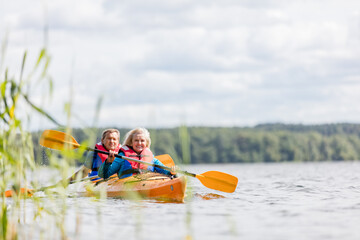 Happy senior active couple kayaking on lake