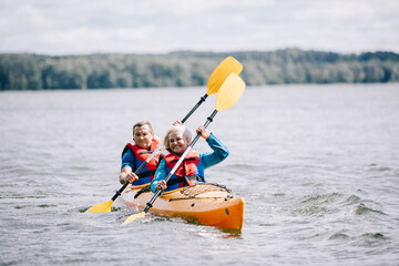Happy senior active couple kayaking on lake