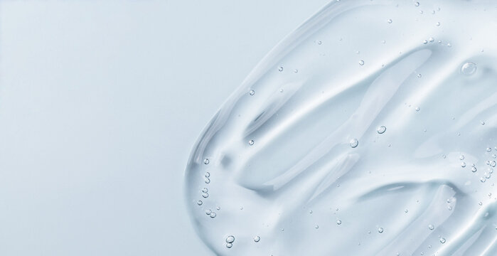 Serum gel smear on blue background. Cosmetic transparent gel serum texture.