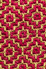 Knitted background with magenta yellow geometric arabic pattern. Crochet mosaic pattern. Rhombus and square pattern.