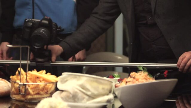 static shot of cameraman shooting food products with DSLR on slider, french fries, curd, risotto, berries, white bread