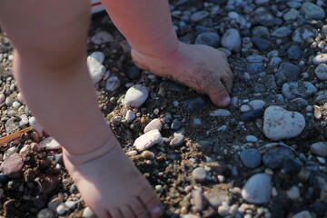 The bare feet of a baby on the pebbles of the beach. Selective focus