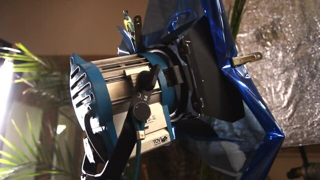 steadicam shot of film production set with spotlight and reflector, blue filter attached to spotlight