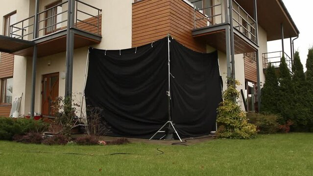panning wide shot of a house from outside with the corner windows covered with black fabrics for filming purposes