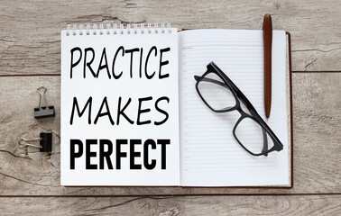 practice makes perfect - text on notepad .top view of an open notepad with glasses.