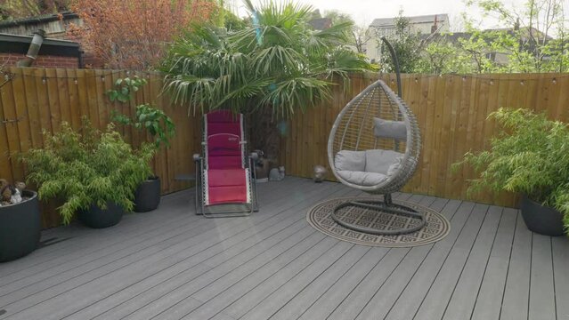 Minimalistic UK summer garden showing swing chair decking and sun lounger.