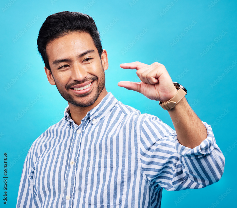 Poster Small, hand and gesture of a man with a smile in studio showing a tiny measurement. Isolated, blue background and male model show happiness and positive opinion with hands from small size sign