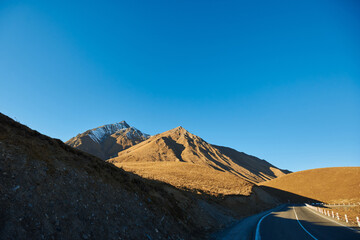 beautiful mountain landscape. ragged mountain peaks, sharp peaks in the snow brown mountains in the snow and an empty asphalt road with white markings goes into the distance