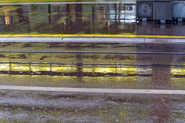 Wet road with yellow reflections road on a rainy spring day at City of Zürich district Oerlikon. Photo taken April 1st, 2023, Zurich, Switzerland.