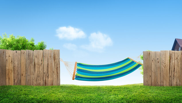 relaxing on hammock in backyard in spring, grass in garden and wooden fence