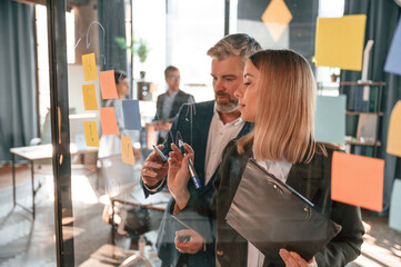 Conception of plan. Many stickers are on the glass. Group of business people are working in the modern office