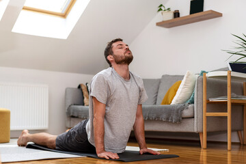 Wrestler man with broken ears doing stretching exercise on yoga mat at home.