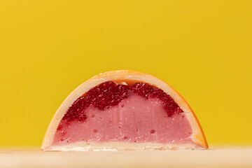 Close up of homemade orange chocolate bonbon slice. Assortment of hand painted candies. Candy cut in a half. Mockup with a copy space. Macro shot of  chocolatier products on yellow background - Powered by Adobe