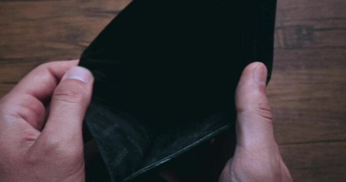Close up man opens an empty wallet with no money and he has nothing to pay with. Poverty, crisis and unemployment. The concept is no money in the wallet.