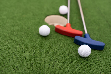 colorful golf putters with golf balls on synthetic grass