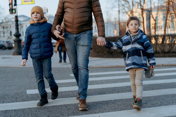 father and children crossing road on pedestrian crosswalk