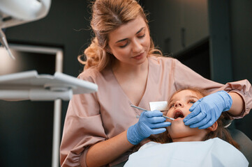 Woman is working with little girl teeth. In the stomatological cabinet