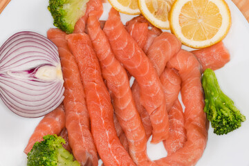Long raw salmon slices among the vegetables and lemon slices