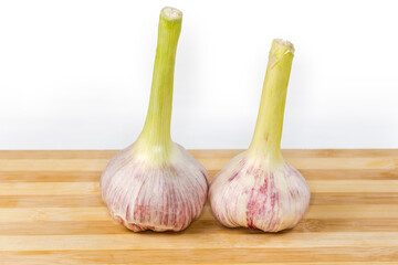 Heads of young purple garlic on cutting board, side view