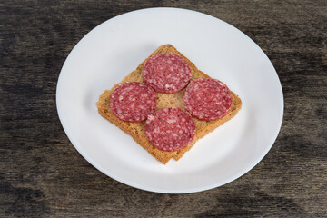 Open sandwich with dry-cured sausage slices on the dish