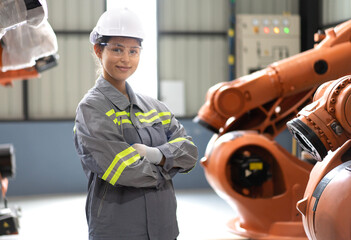 Portrait of female industrial engineer in white hardhat standing with automated robotic machine as working on robot maintenance in futuristic technology factory. Modern woman empowerment in industry. - obrazy, fototapety, plakaty