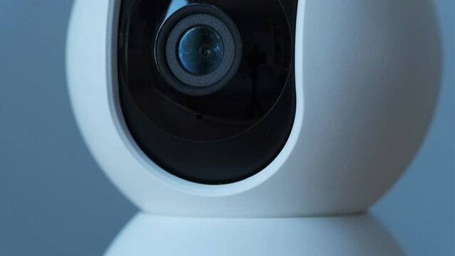 Macro shot of home surveillance camera.  Security camera lens moving while scanning the room. Safety and theft protection concept