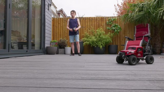 Young boy at home outdoors in the garden playing with his RC Car, Truck, 4 x 4