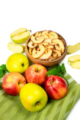 Dry apple slices in a bowl and fresh apples on white background. Dehydrated snacks of apple fruits. Healthy, no sugar sweet food. Candied fruit