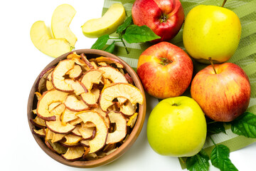 Dry apple slices in a bowl and fresh apples on white background. Dehydrated snacks of apple fruits. Healthy, no sugar sweet food. Candied fruit