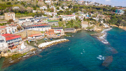 Aerial view of the seaside village of Marechiaro which is located in the Posillipo district of Naples, Italy. There are small boats anchored in the artificial harbour.