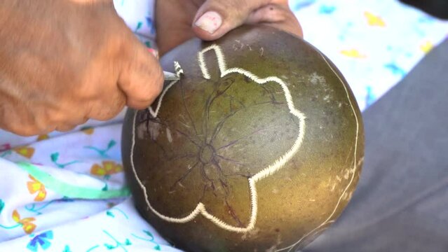 The ancient craft of mask-making at the Boruca Community, Costa Rica, detail shot of a person carving a drawing on a concave surface.

