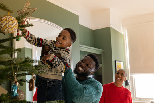 Father lifting son to put the star on the Christmas tree