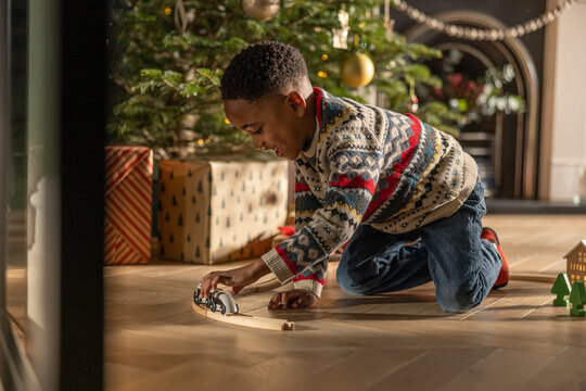 African American boy playing with traditional train toy on Christmas Day