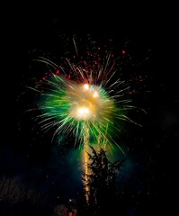 Vertical shot of green orange red fireworks in a foggy night sky. Italy