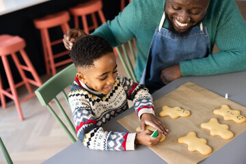 Father and Son decorating gingerbread men together at Christmas