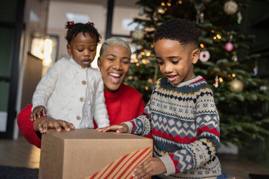 Mother with son and daughter at Christmas time opening a present