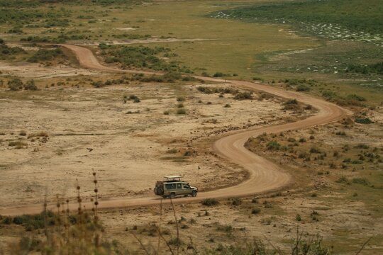 Aerial View Of A Vehicle Driving On A Dirt Road On An Open Field