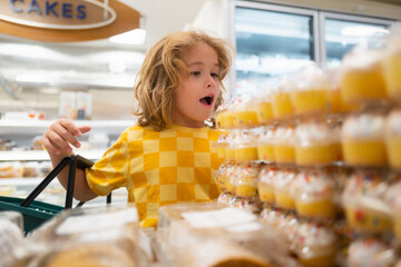 Kid choosing cakes, cupcake muffin. Kid at supermarket. Child choosing food in store or grocery store.