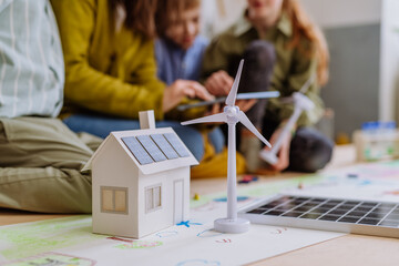 Close-up of house model with solar system and wind turbine during a school lesson.