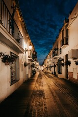 narrow cobblestone street, evening, street lamps, buildings