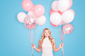 Portrait of trendy cheerful elegant girlfriend having many white air balloons in two hands looking...