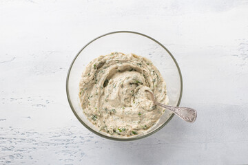 Glass bowl with dough for cottage cheese buckwheat flatbread with greens on a light blue background, top view