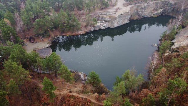 Picturesque aerial view of landscape with emerald lake and rocks in the middle of a coniferous autumn forest in Korostyshiv granite quarry, Zhytomyr district, northern Ukraine. Zhytomyr canyon.