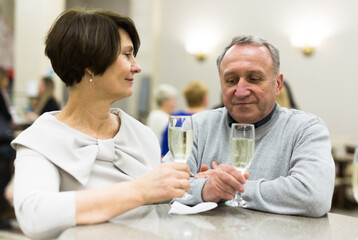 Obraz premium Mature man and woman drinking champagne in theater lobby
